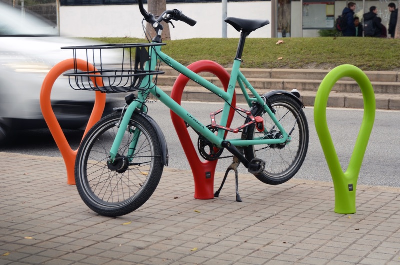 Loclock fietsbeugel fietsstandaard van beton met kunststof ronde buis beetje ovaal gevormd als een druppel in het roze groen zwart grijs wit paars rood geel blauw en grijs voor de openbare ruimte winkelgebieden kantoren bedrijven voor parkeren fiets