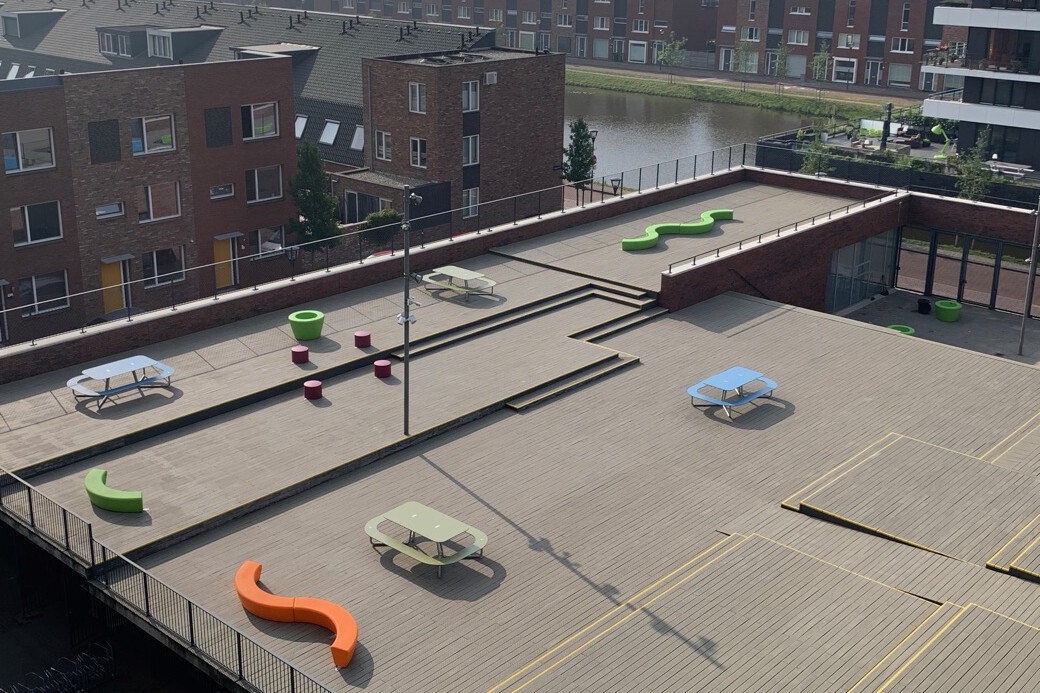 Meubilair op het schoolplein van Haarlem College met blauwe Plateau bank met rugleuning met onderstel van staal en groene plantenbak