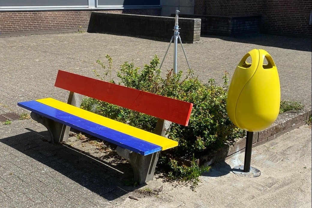 Tulpi bin afvalbak in de vorm van een tulp bloem voor het schoolplein van ROC Mondriaan met een bank in verschillende kleuren geel rood en blauw